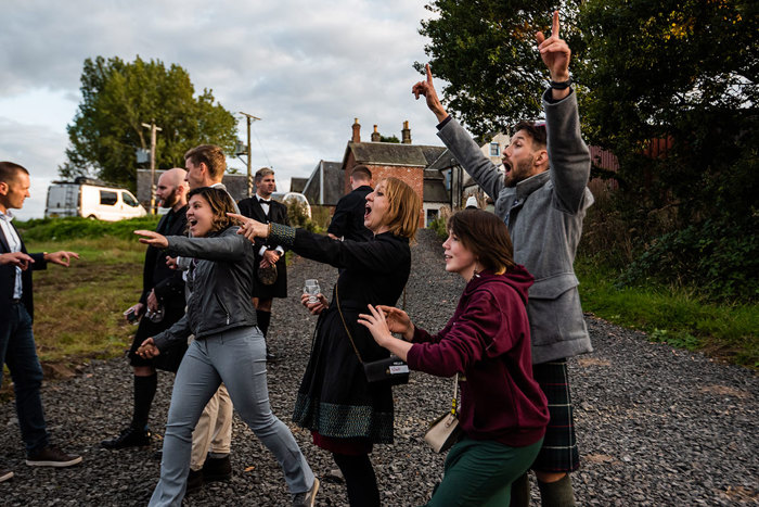 A Group Of People Standing Outside While Pointing And Cheering