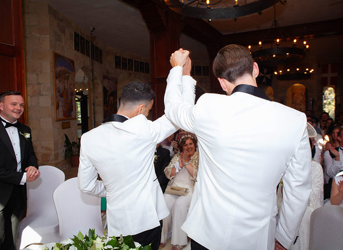 two men wearing white jackets raising their hands up in celebration