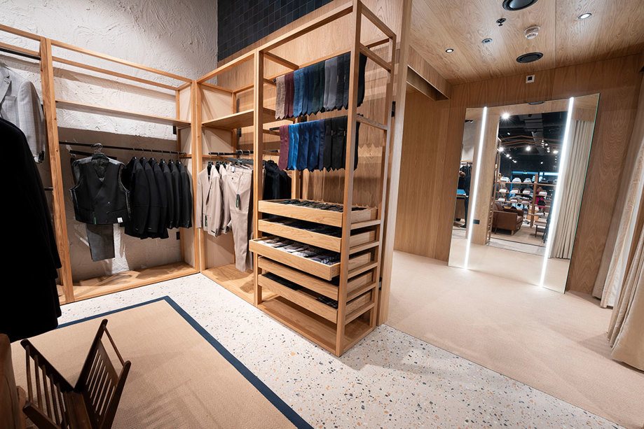 Wooden shelving with clothes and fitting room at Remus Uomo Braehead