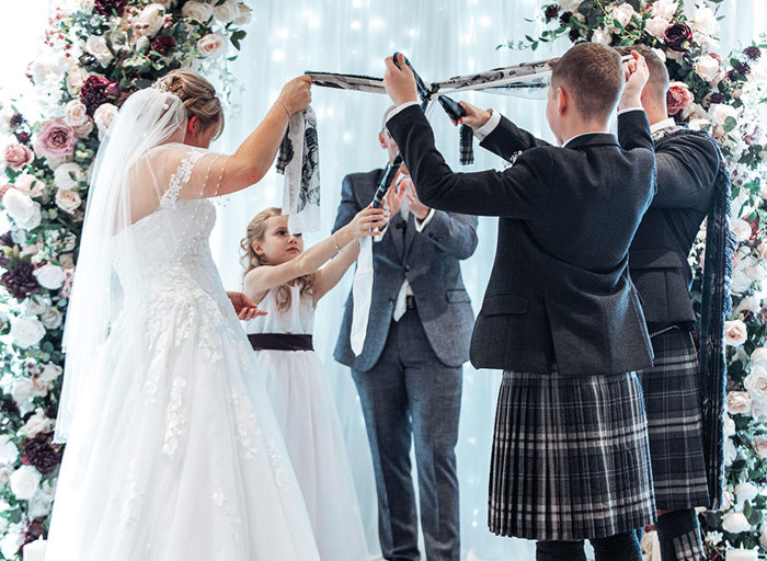 bride and groom joined by guests for a handfasting