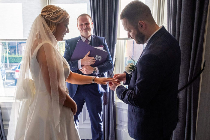 Groom putting ring on bride's finger