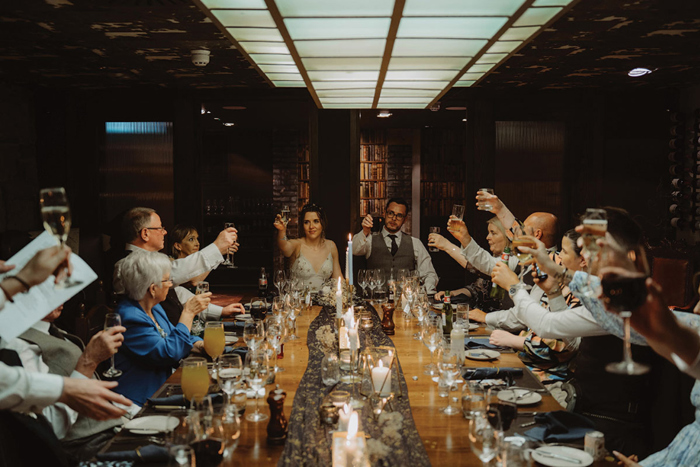 Bride, groom and guests cheers during wedding meal