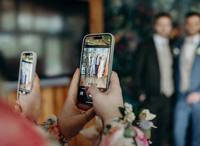 a person taking a photograph of people at a wedding on a smart phone