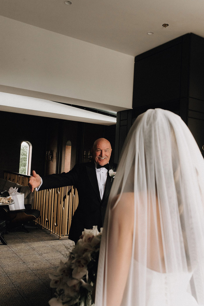 a man in a suit holding his arms open to embrace a bride.