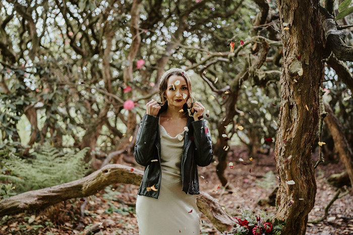 Bride in forrest with black leather jacket over her wedding dress