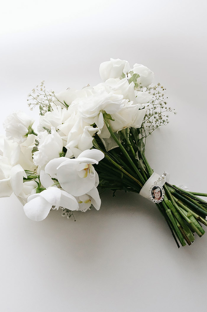 white bridal bouquet of flowers with photo charm tied around the stems