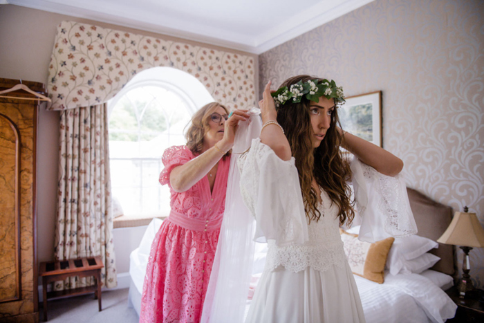 A Lady Wearing A Pink Dress Helping A Bride Fix Her Veil