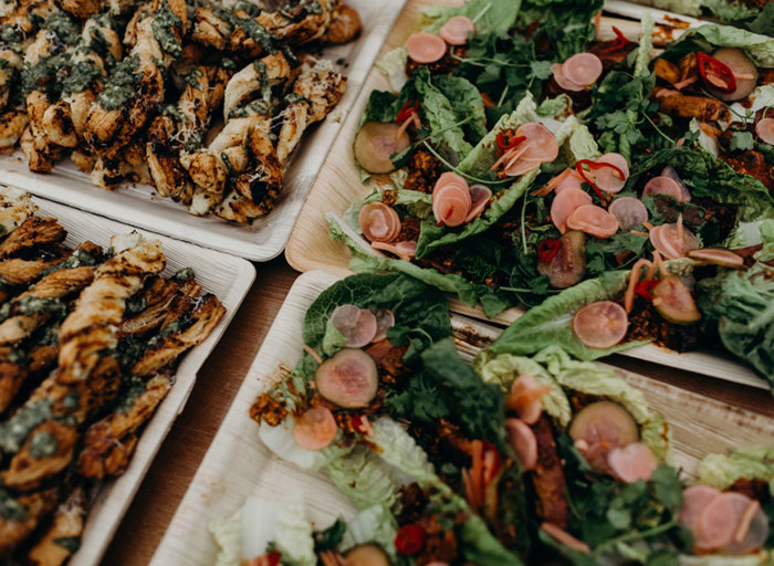 close up of pastry twists and salads on wooden trays