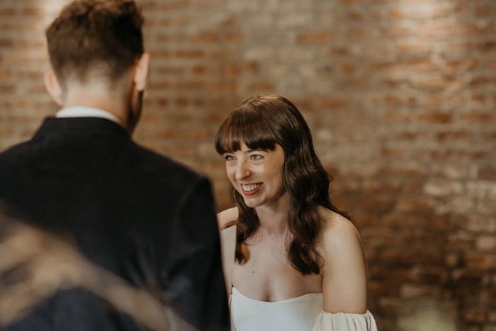 Bride smiles during the ceremony while facing groom