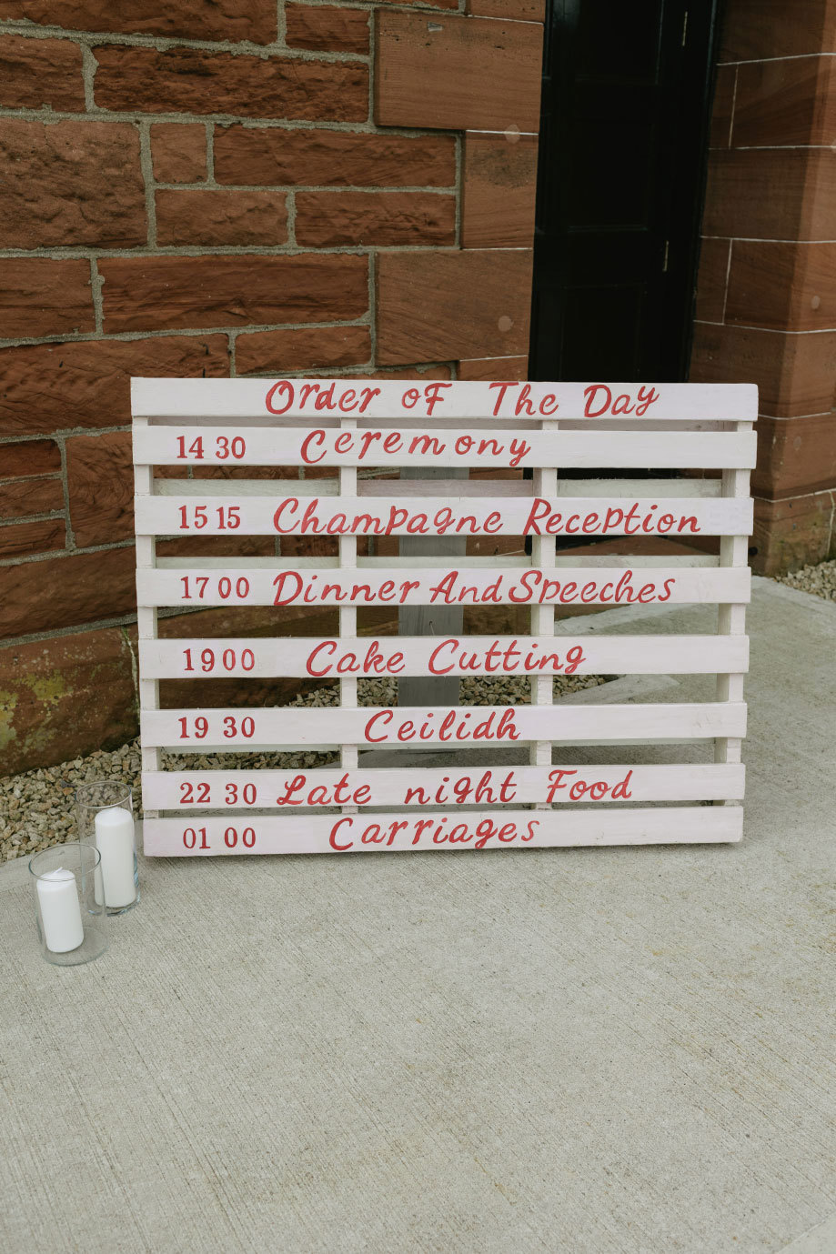 a wooden pallet painted red and white with a wedding order of the day