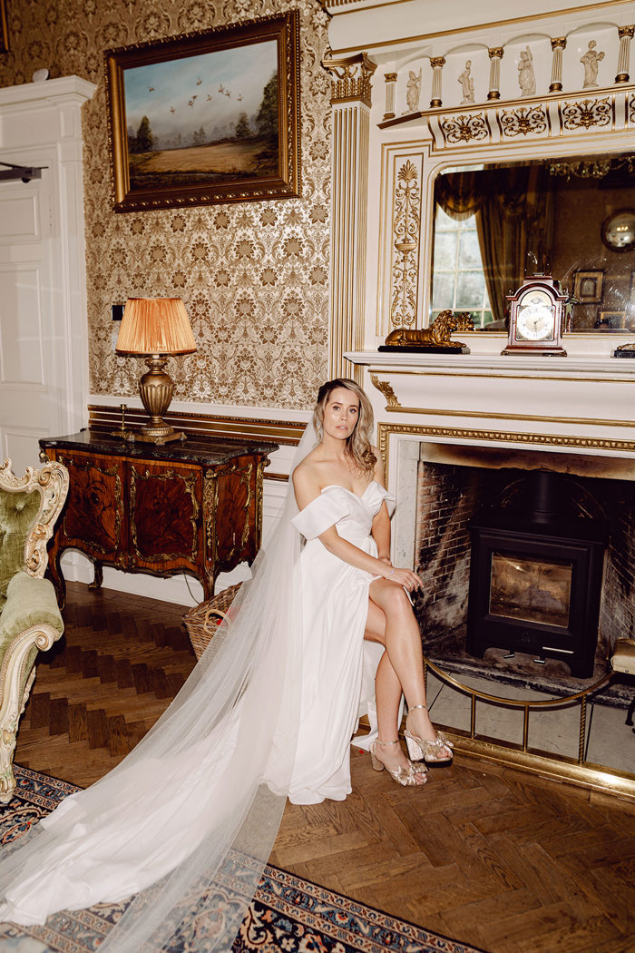 bride sits down to show off wedding dress with long veil