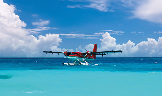 a red sea plane skimming the surface of a crystal blue ocean