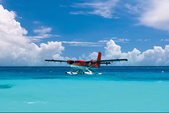 a red sea plane skimming the surface of a crystal blue ocean