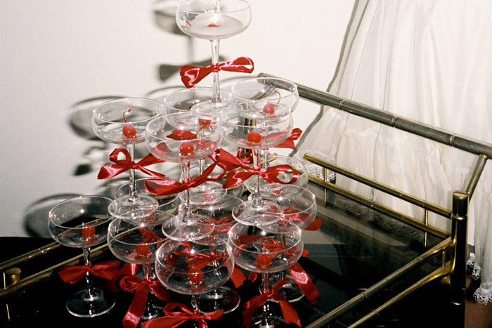 champagne tower of coupe glasses with red bows around the stems, all placed on a cocktail trolley