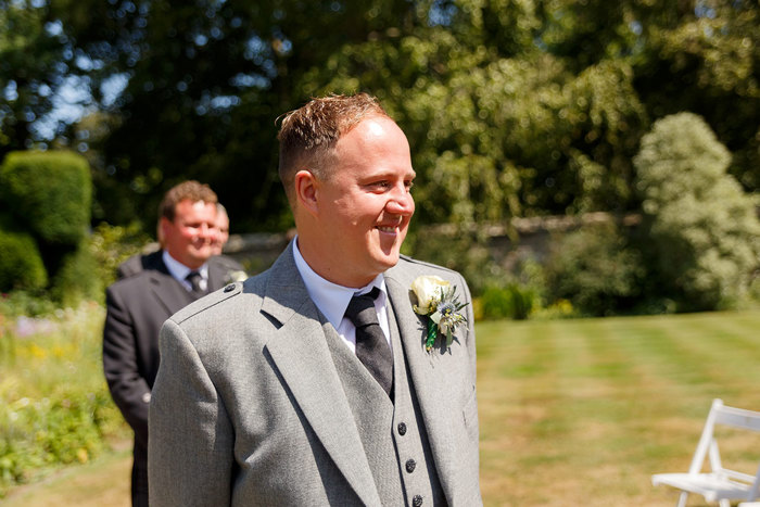 A close up photo of a man in a grey jacket, shirt and tie smiling