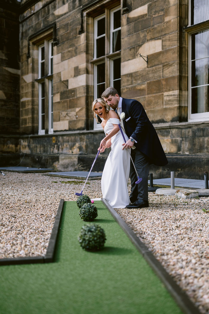 A bride and groom playing mini golf outside Mar Hall.