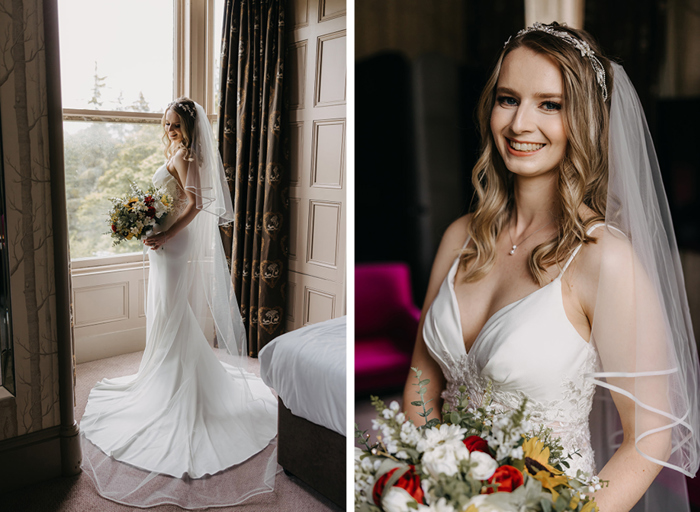 A bride in a floor length dress stands by a window looking back at the camera and holding a colourful bouquet