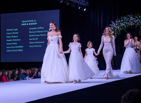 a catwalk with female models wearing wedding dresses and young girl models in frilly dresses too