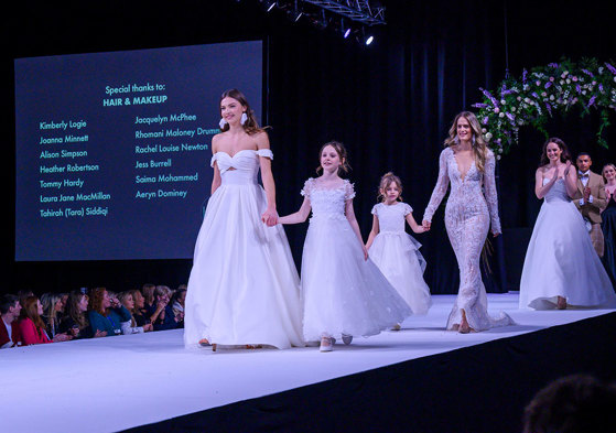 a catwalk with female models wearing wedding dresses and young girl models in frilly dresses too