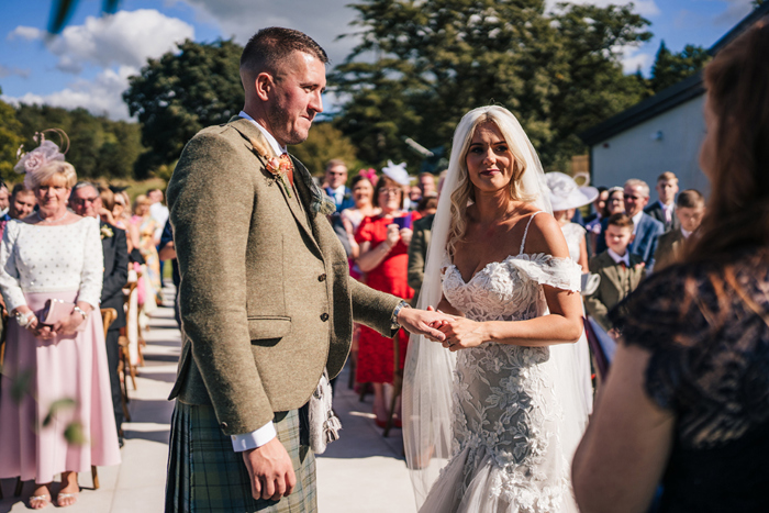 Bride and groom hold hands during the ceremony 