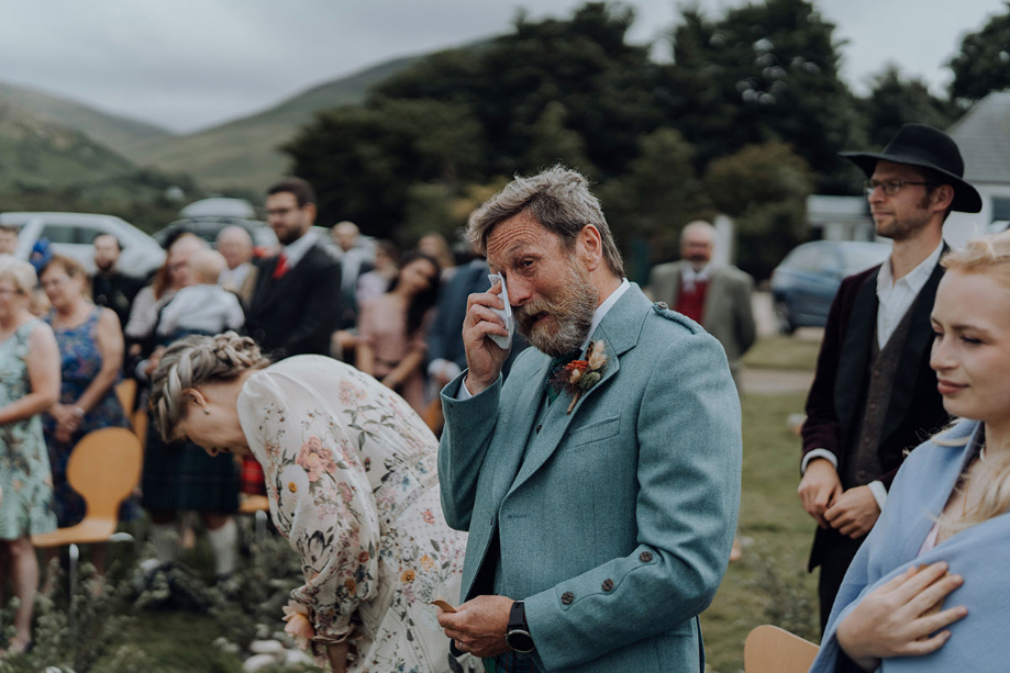 Father of the bride wipes tears during ceremony