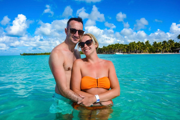 couple wearing swimsuits stood with arms around each other in the ocean 