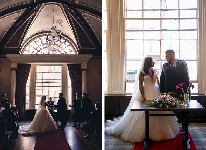 A bride and groom during their ceremony standing in front of a large window 