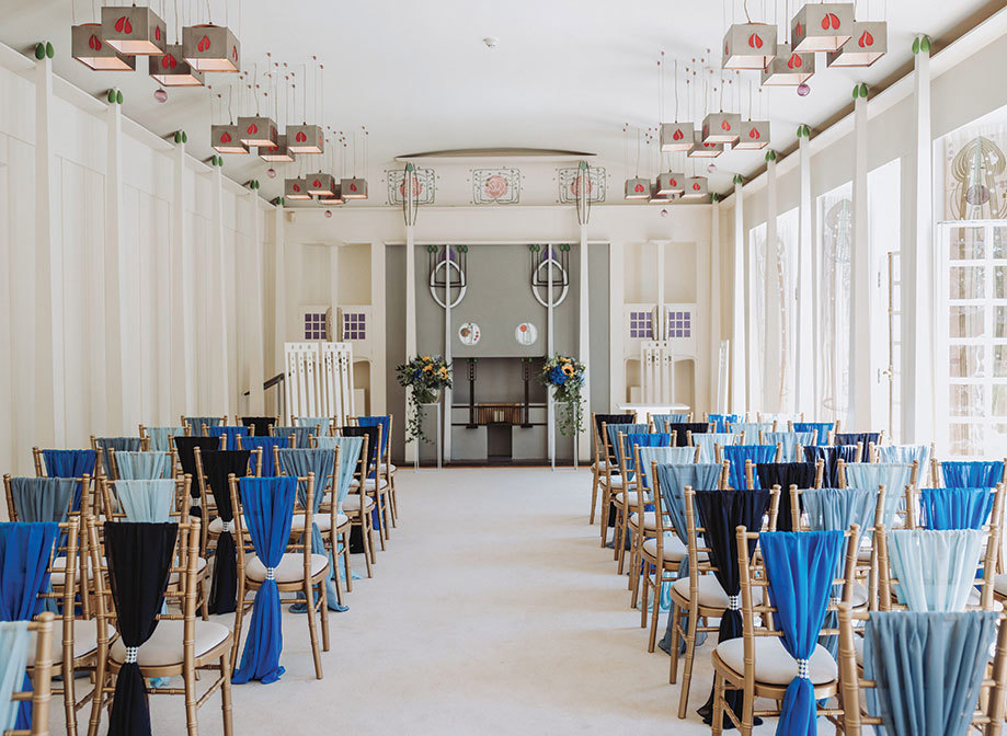 The Music Room at House for an Art Lover set for a wedding ceremony with rows of chiavari chairs decorated with blue drapes