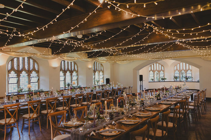 A room with long tables and chairs and lights. 