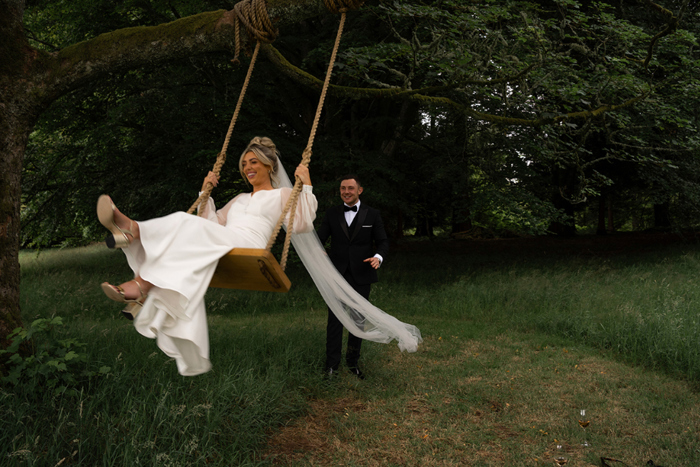 Groom pushes bride on a swing