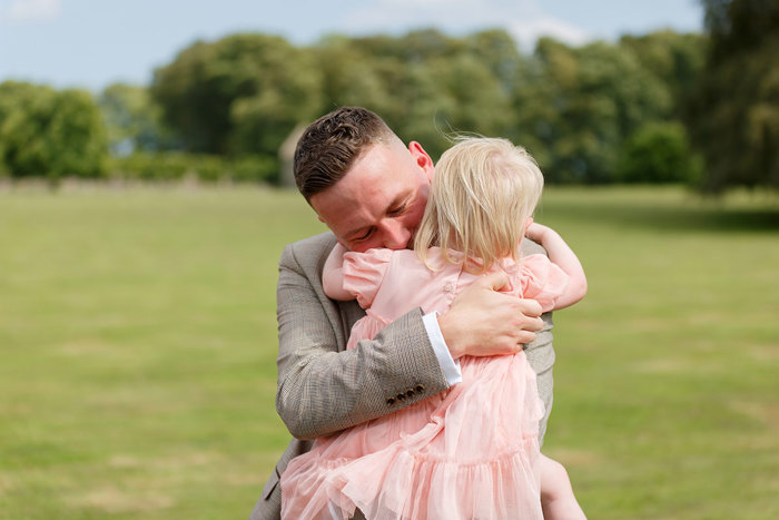 A man in a grey suit holding a child in a pink dress