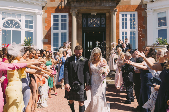 Confetti thrown at happy couple as they walk out of their venue