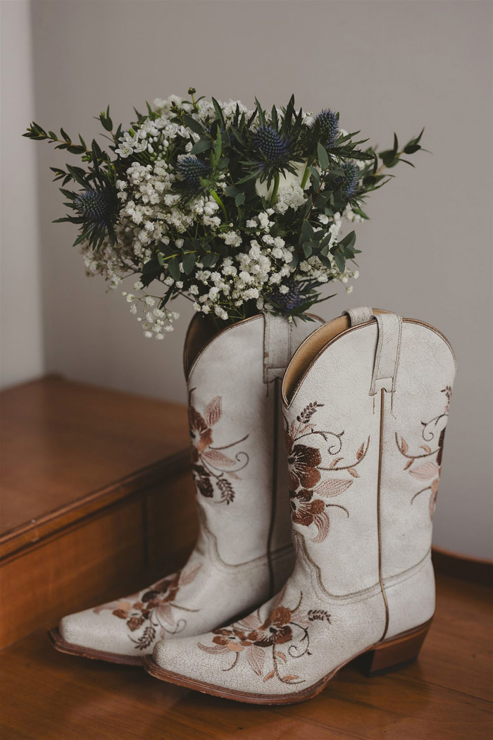 a pair of white cowboy boots with flowers in them.