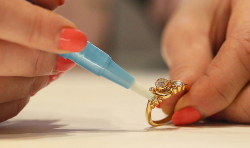 a pair of manicured hands cleaning a gold diamond ring