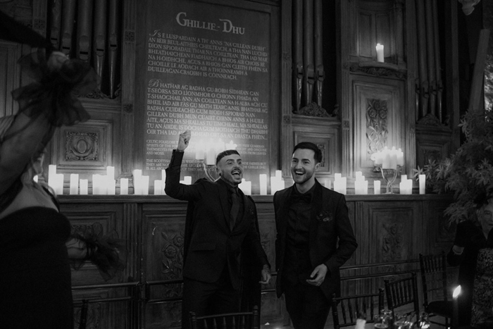 Two People Wearing Black Standing In Front Of Candles