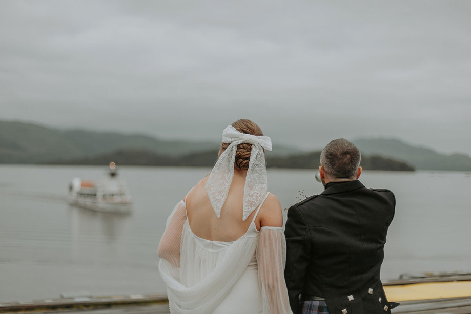 Couple overlook loch with boat in the distance