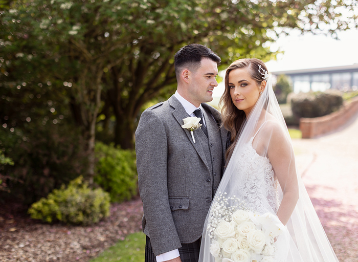 a bride and groom posing for a portrait in the gardens of Lochside House Hotel