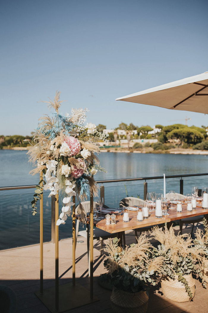 A table with flowers and candles on it next to a body of water