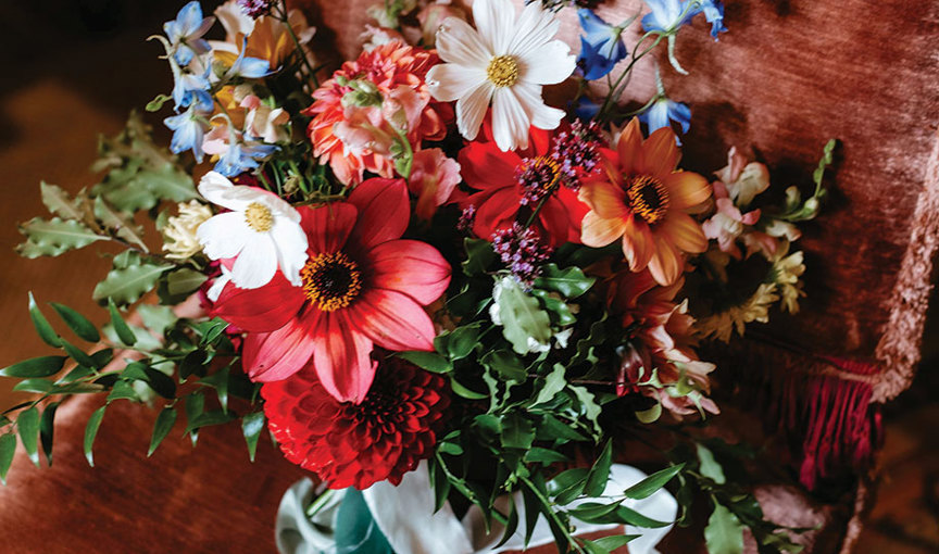 a colourful artfully arranged bouquet of flowers on a dark pink velvet chair