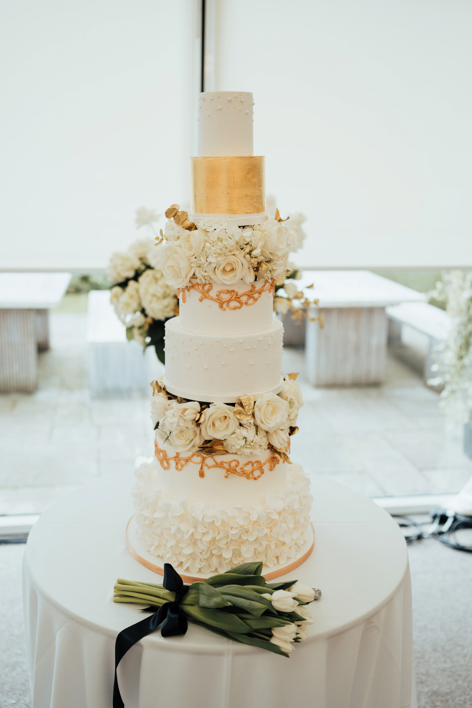 A six tier wedding cake with gold details and white flowers