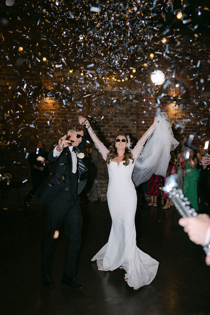 A bride and groom dancing in a room with confetti