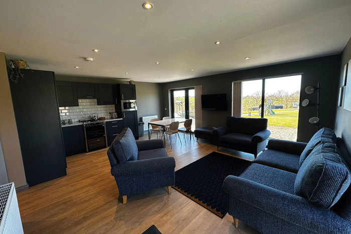 The inside of a chalet filled with blue furniture and an open kitchen