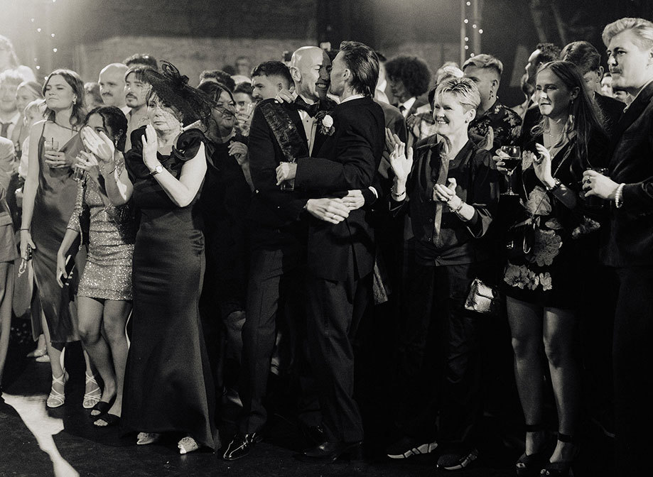 David And Alistair Black And White Grooms Embracing With Guests