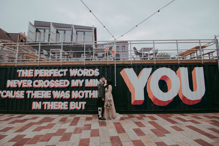 Bride and groom stand in front of street art