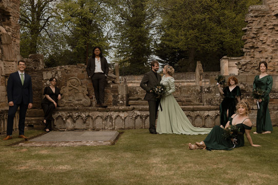 a wedding group posing in the graveyard at Elgin Cathedral