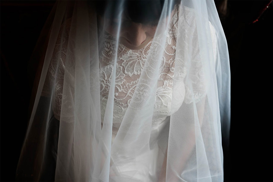 A photo taken from above of a woman wearing a white lace dress and a veil over her head