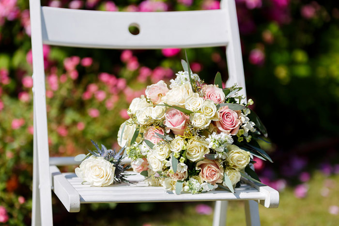 a bouquet of pink and white roses on a white wooden chair 