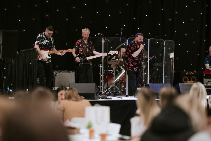 A group of men playing instruments on a stage at the Scottish Wedding Show.