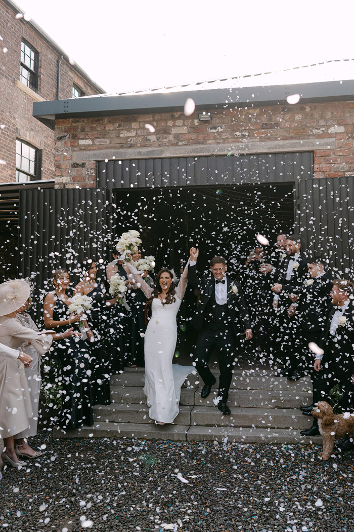 A bride and groom outside the Engine Works with confetti falling