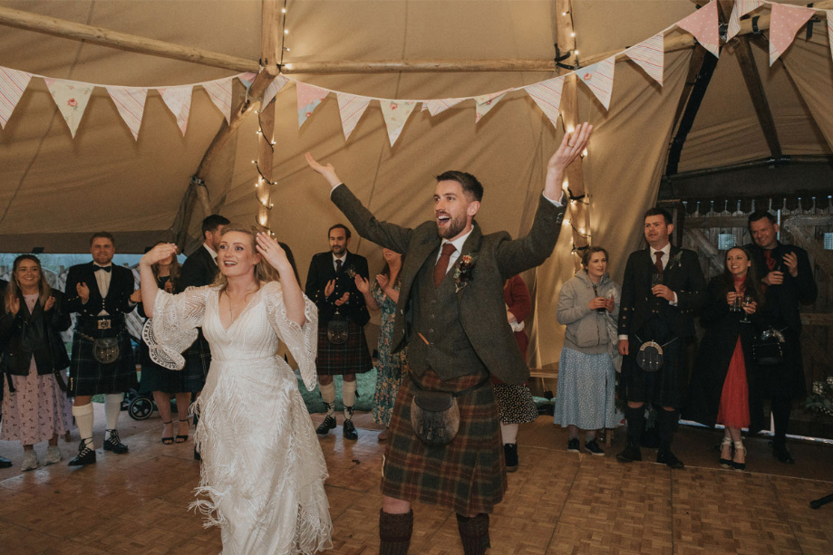 Couple throw their hands up in the air while on the dancefloor